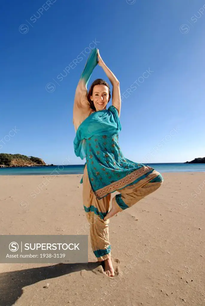 Yoga teacher and artist Lena Tancredi doing Tree Pose on the beach, Ibiza Island, Balearic Islands, Spain