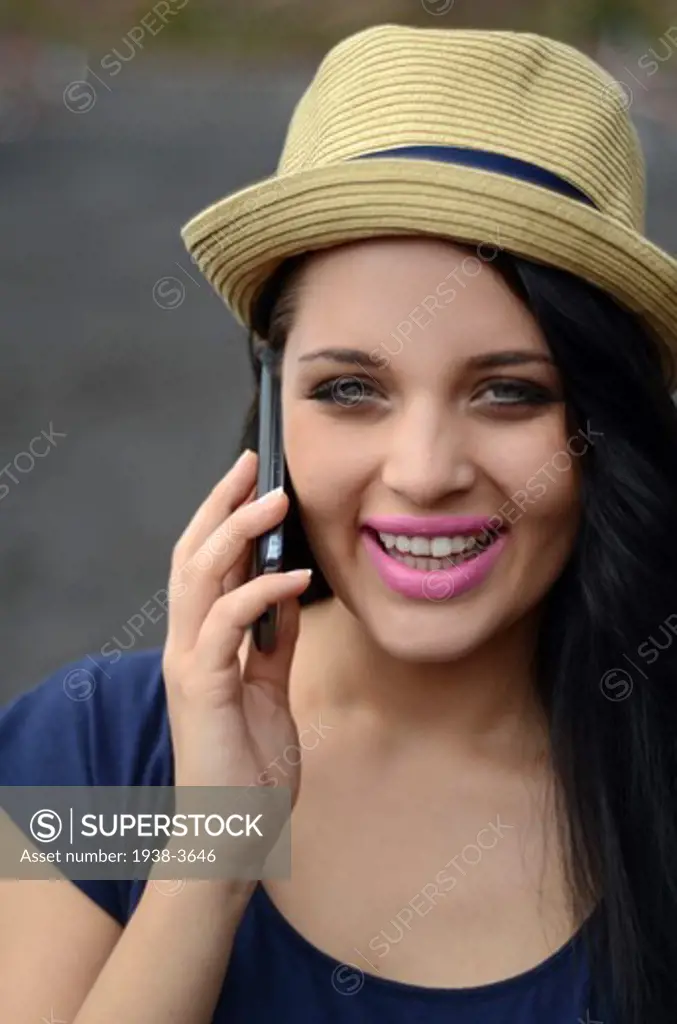 Cute brunette teenager on the beach, talking on the mobile telephone.