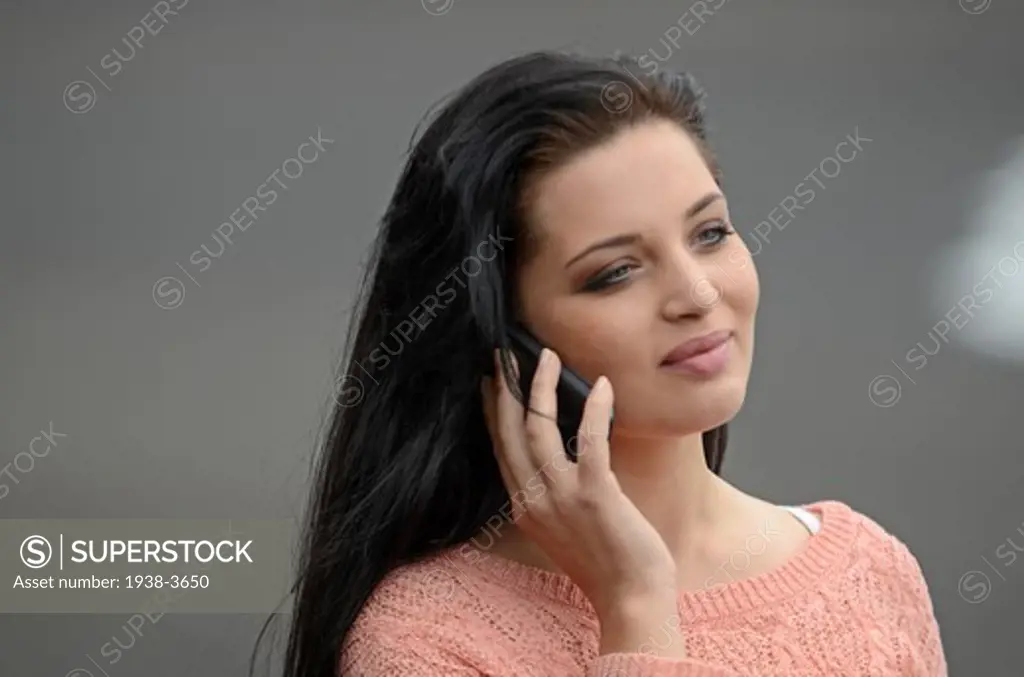 Cute brunette teenager on the beach, talking on the mobile telephone.