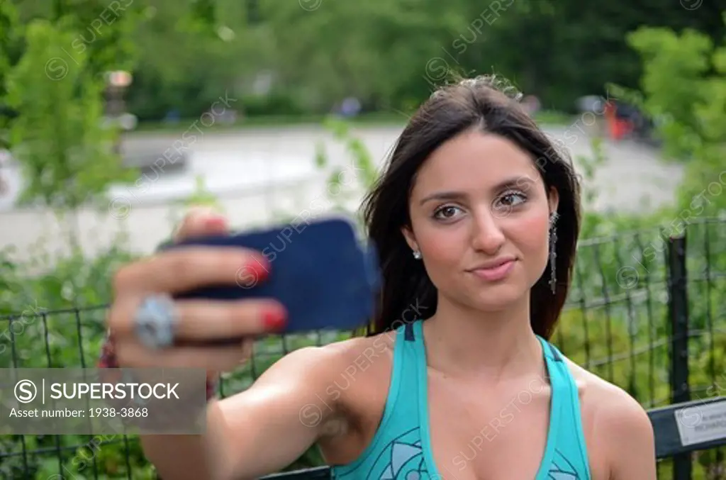 Attractive young mixed race woman taking a self portrait with phone in Central Park, New York City