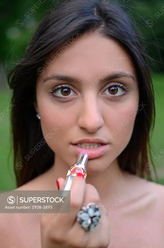 Attractive young mixed race woman painting her lips, New York City