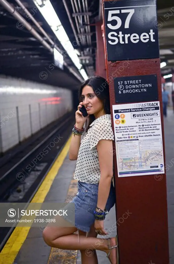 Attractive young mixed race woman talking with mobile phone in subway station, New York City