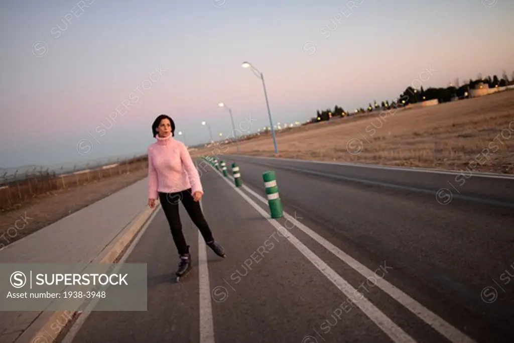 Young attractive woman skates on rollerblades at sunset
