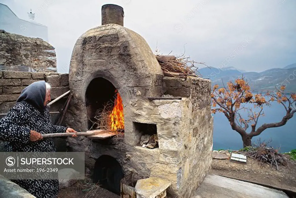 Greece, Astipalea, Woman at stone oven