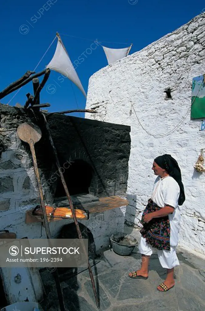 Greece, Dodecanese, Karpathos, Woman using stone oven