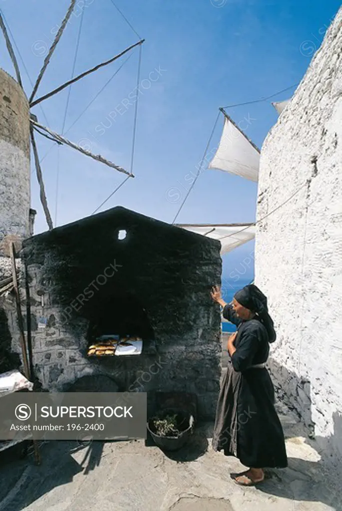 Greece, Dodecanese, Karpathos, Woman using stone oven