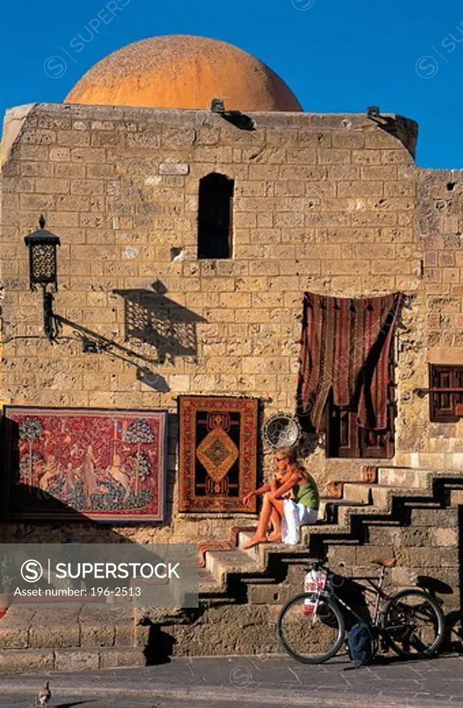 Greece, Dodecanese, Rhodes Island, Tourist sitting in front of traditional building