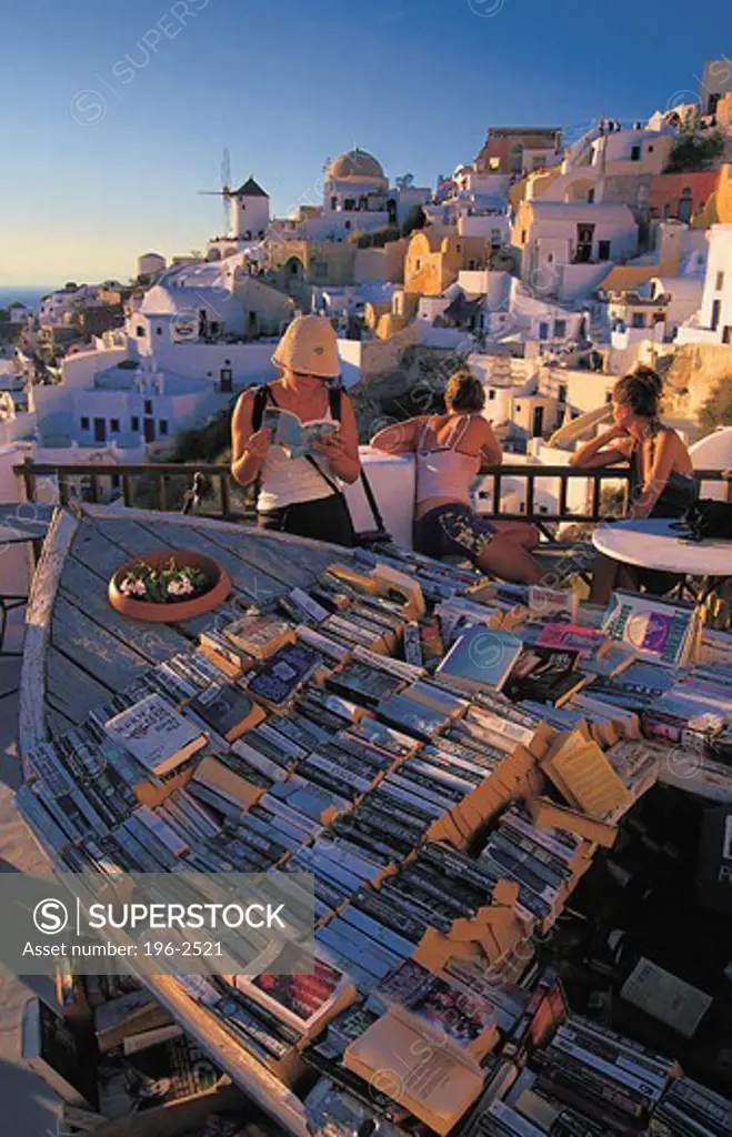 Greece, Cyclades, Santorini Island, Tourists reading books in Greek town