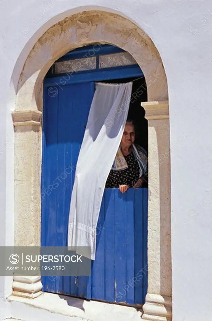 Greece, Cyclades, Tinos island, Pyrgos village, Woman looking through door