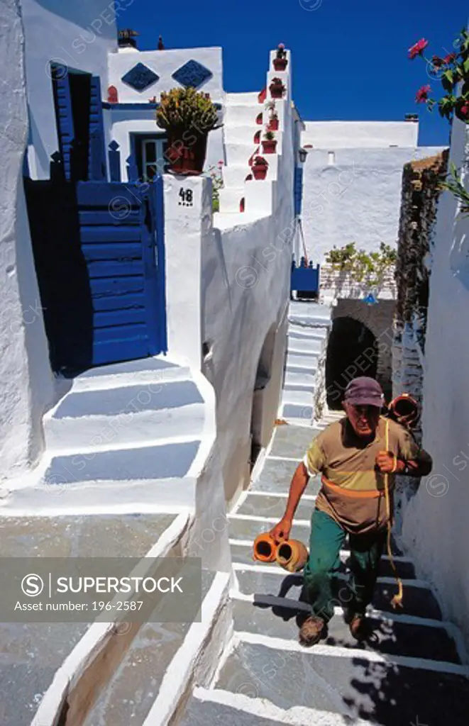 Greece, Cyclades, Tinos island, Smardakito village, Local man walking up steps towards house