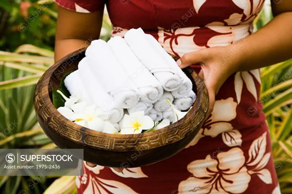 Woman holding rolled towels and flowers in a basket, Bora Bora, Tahiti, French Polynesia