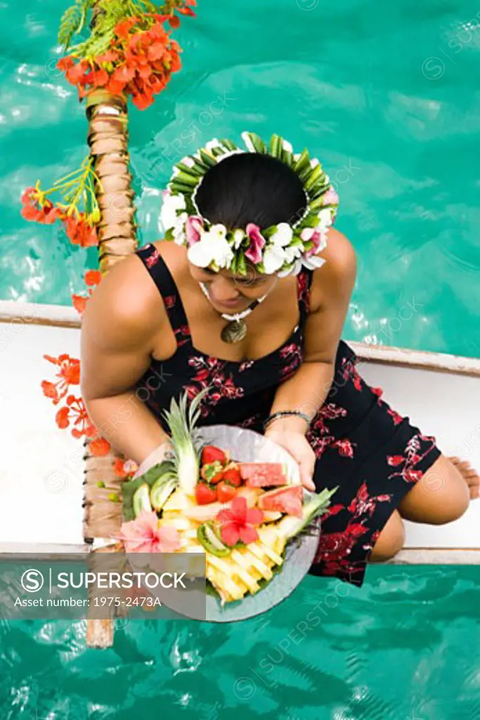 High angle view of a woman holding a plate of fruit salad on a canoe, Bora Bora, Tahiti, French Polynesia