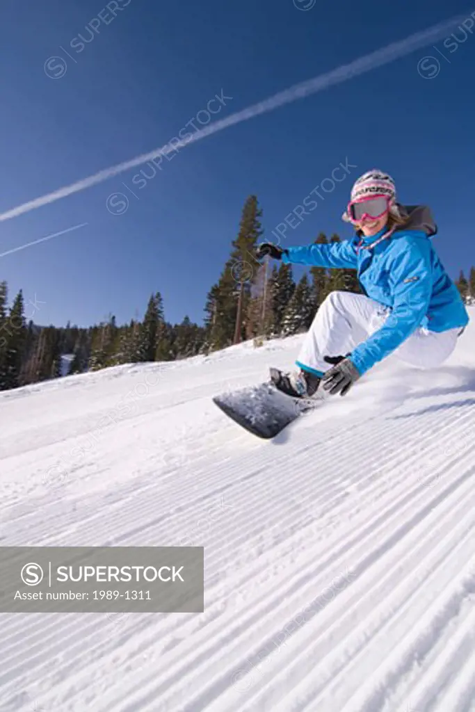 A woman snowboarding on a sunny day on freshly groomed snow at Northstar near Lake Tahoe in California