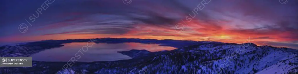 A panorama of Lake Tahoe in California at sunset with alpenglow and clouds