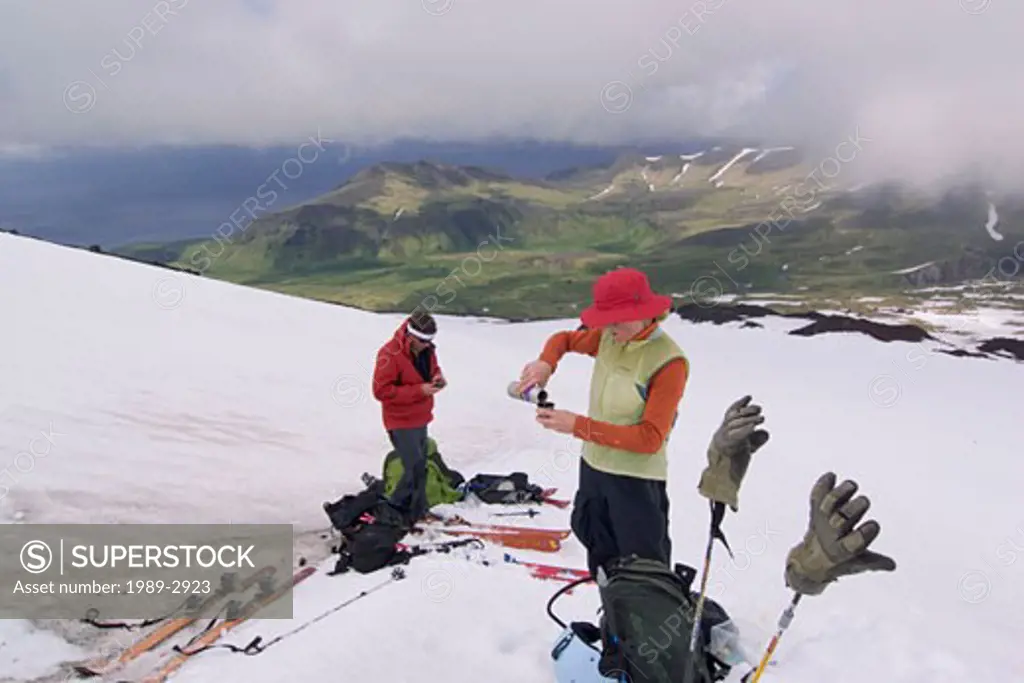 A couple taking a break while climbing Mount Vsesevidov in the Aleutian Islands in Alaska