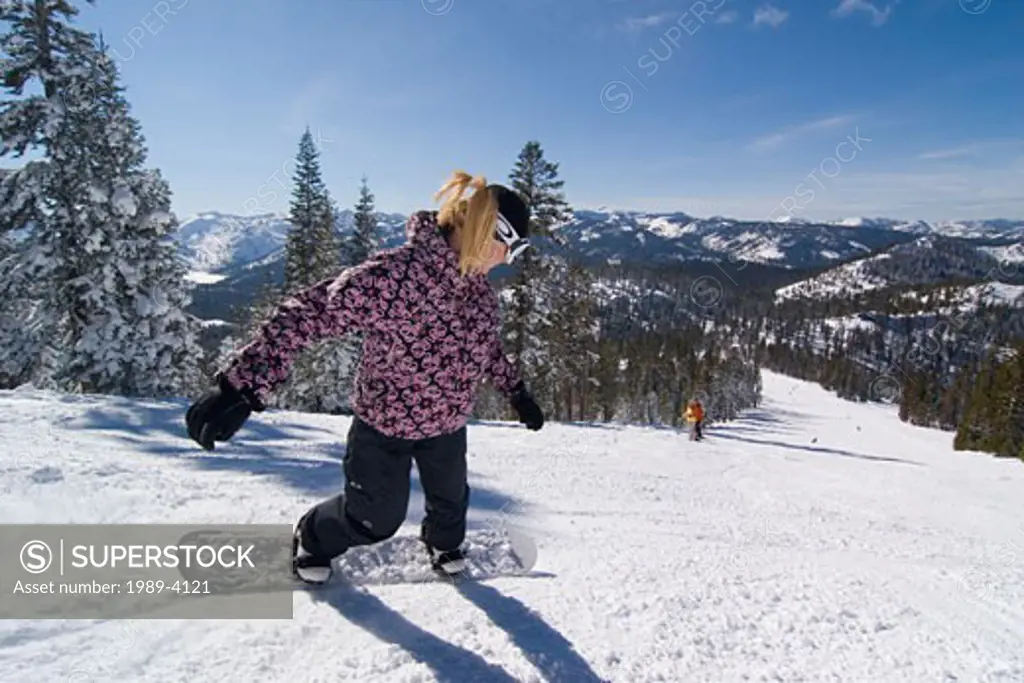 A woman snowboarding on a groomed run at Northstar ski area near Lake Tahoe in California