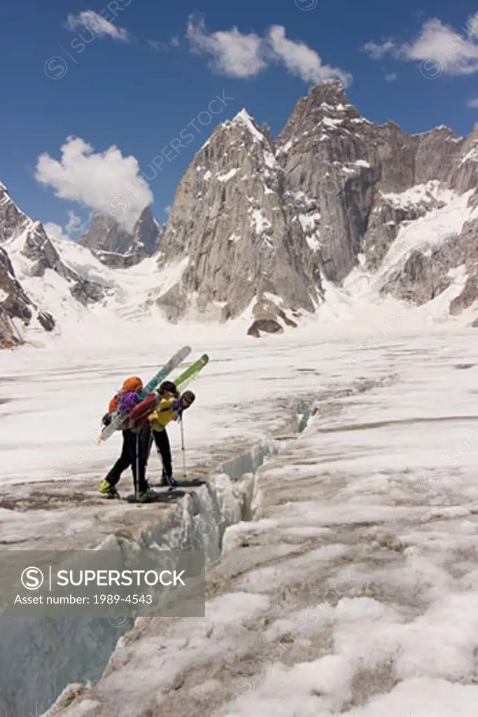Two women ski mountaineers looking into a crevasse on the Biafo glacier in the Karakoram mountains of Pakistan