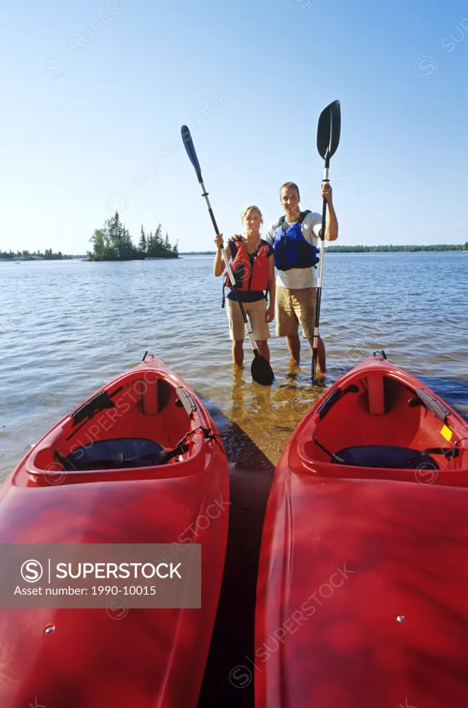 Couple with kayaks at Otter Falls Campground, Whiteshell Provincial Park, Manitoba, Canada.