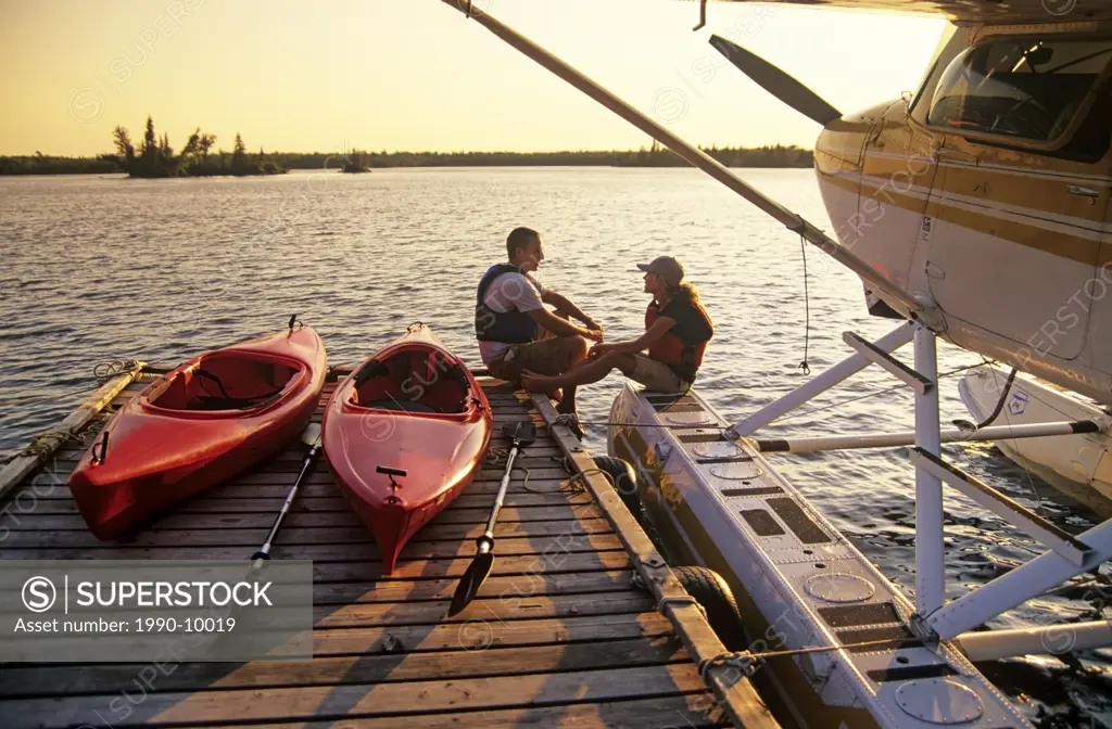 Couple with kayaks on dock, Otter Falls, Whiteshell Provincial Park, Manitoba, Canada.