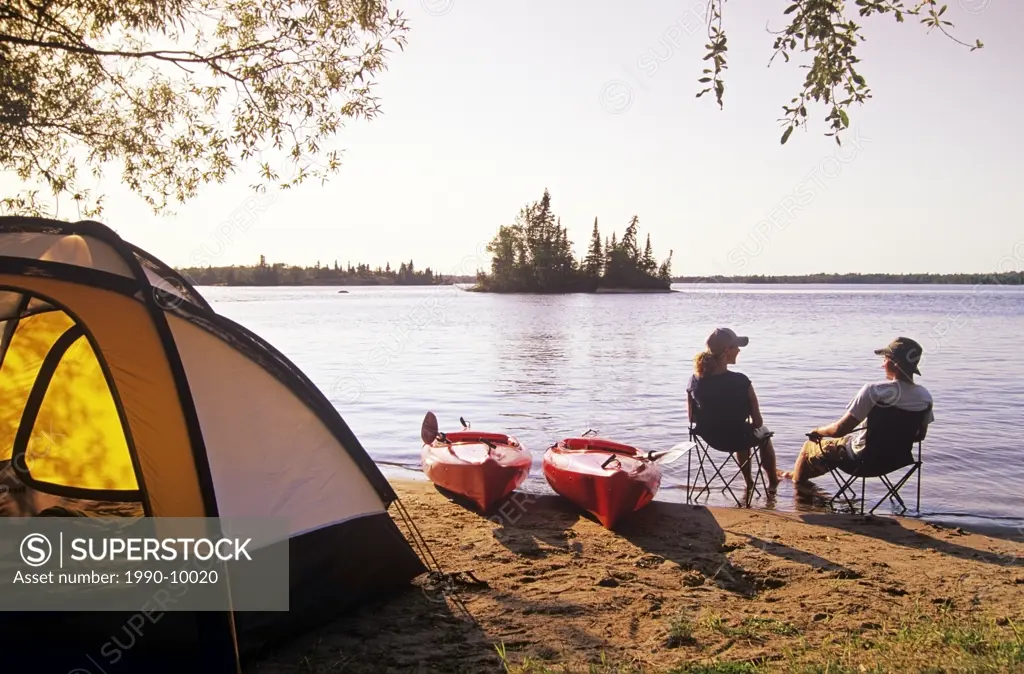 Couple relaxing at Otter Falls campground Whiteshell Provincial Park, Manitoba, Canada.