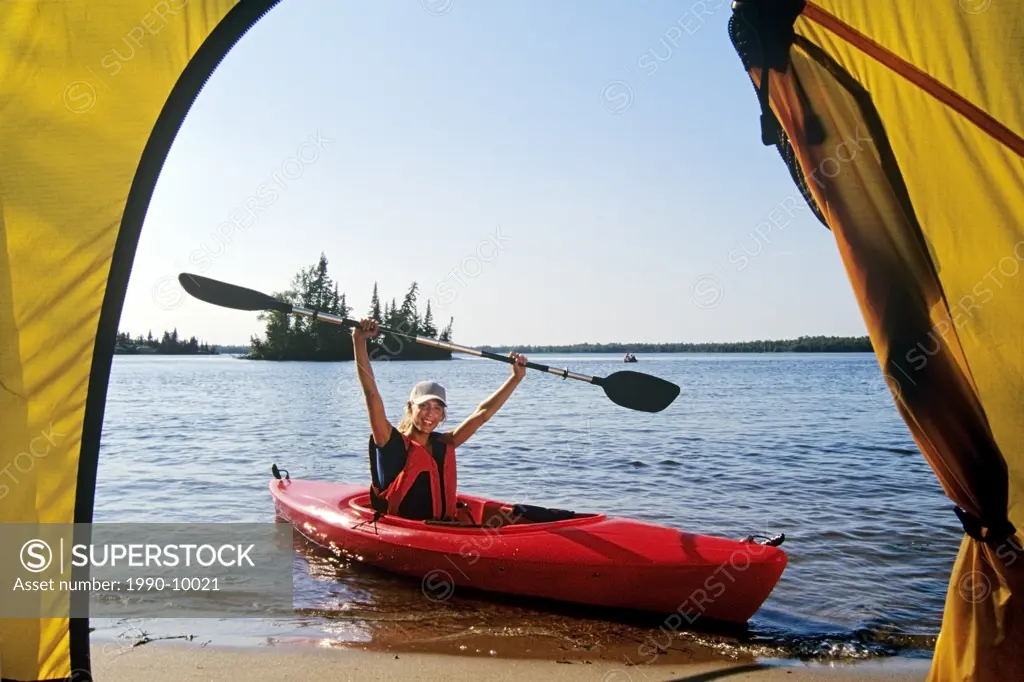 Female with kayak at Otter Falls campground, Whiteshell Provincial Park, Manitoba, Canada.