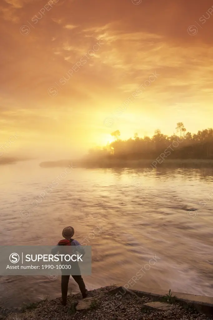 Hiker along the Whiteshell River at sunrise, Whiteshell Provincial Park, Manitoba, Canada.