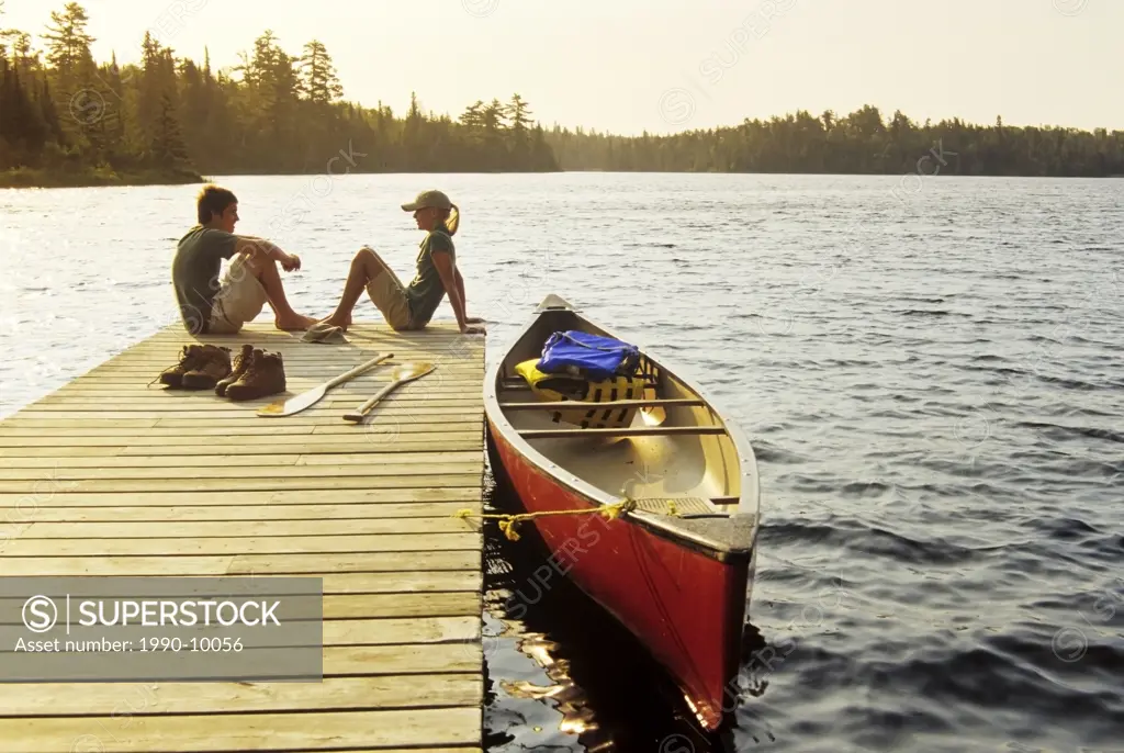 Teens on dock, Lyons lake, Whiteshell Provincial Park, Manitoba, Canada.