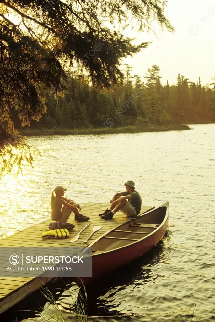 Teens on dock, Lyons Lake, Whiteshell Provincial Park, Manitoba, Canada.