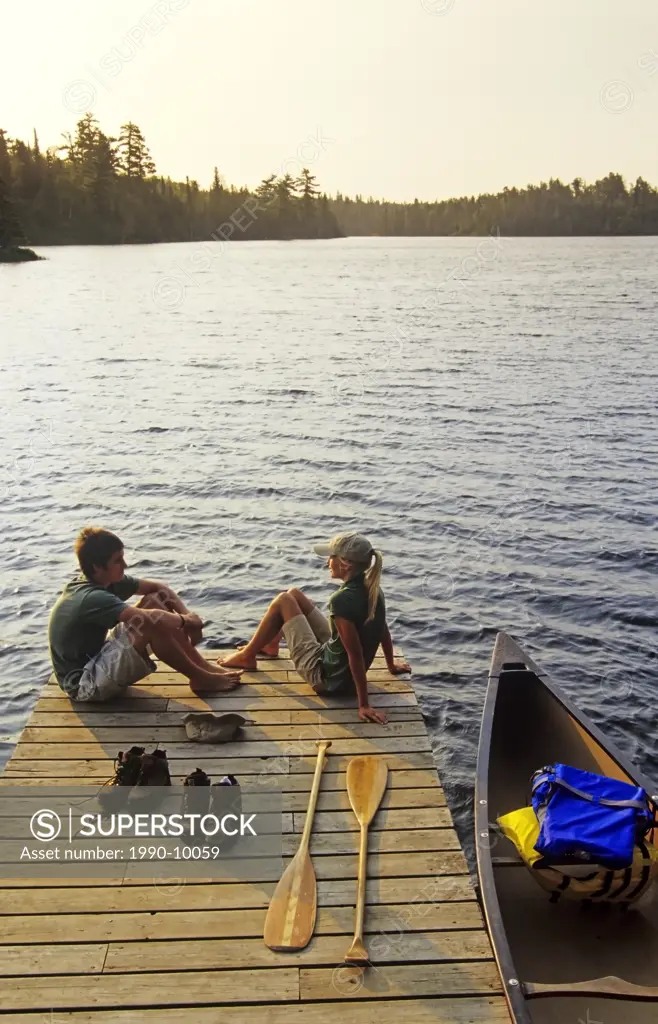 Teens on dock, Lyons Lake, Whiteshell Provincial Park, Manitoba, Canada.