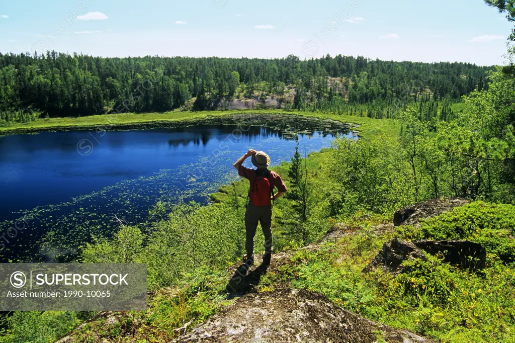 Hiker looking out over the Lilly Pond,Whiteshell Provincial Park, Manitoba, Canada.