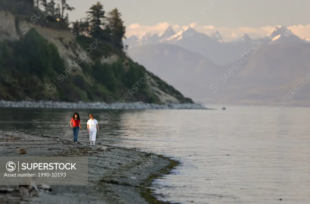 Two ladies strolling along the beach in the evening at Goose Spit, in Comox. Vancouver Island, British Columbia, Canada