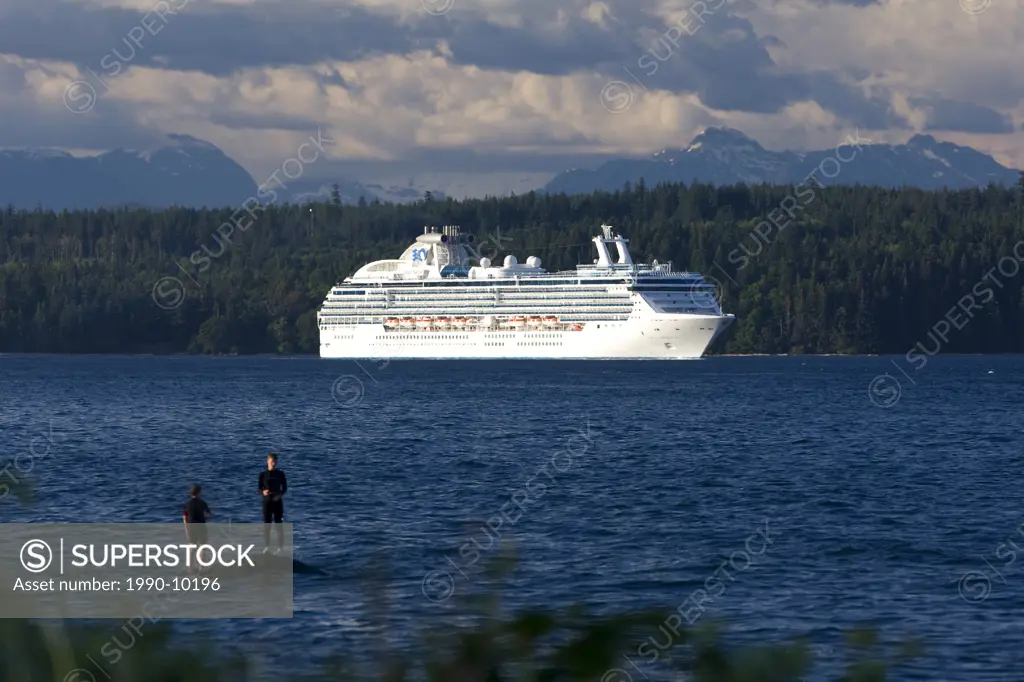 Two boys fishing while a Cruise Ship enroute to Vancouver passes thru Discovery Passage, Campbell River, Vancouver Island, British Columbia, Canada