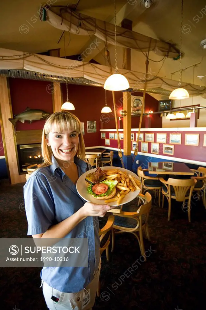 Female server at the Quarterdeck Pub with a hamburger platter. Port Hardy, Vancouver Island, British Columbia, Canada.