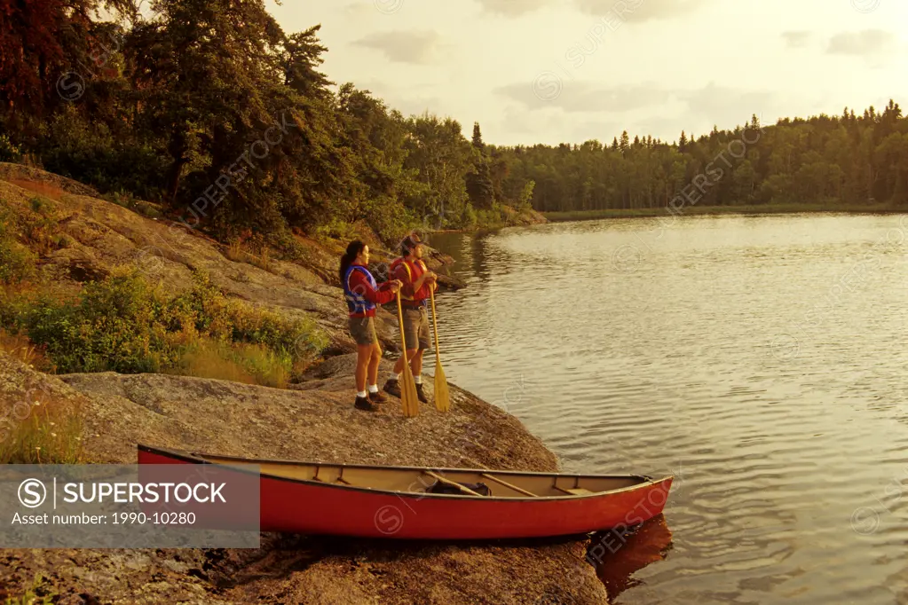 couple with canoe along Big Whiteshell Lake, Whiteshell Provincial Park, Manitoba, Canada