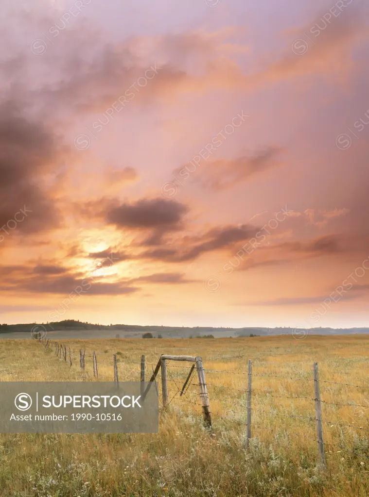 Fence and sunset near Cochrane, Alberta, Canada.
