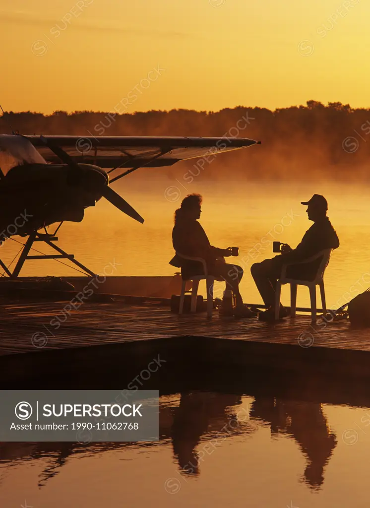 a couple relaxes on a float plane dock, Manitoba, Canada