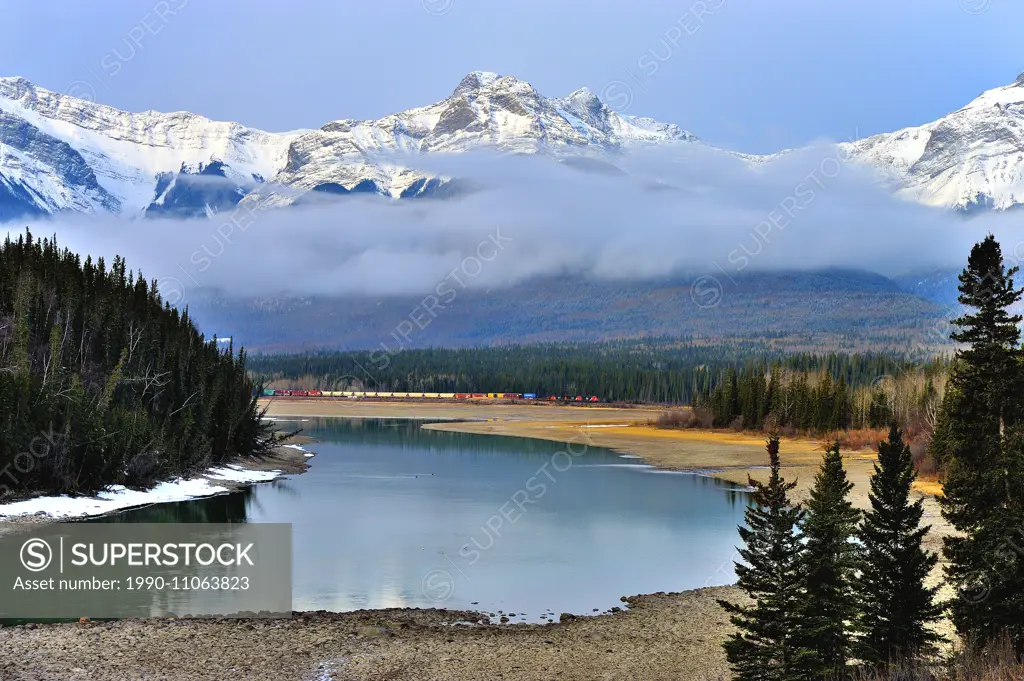 Swan Landing on the Athabasca river with snow-capped rocky mountains at Brule Alberta with a Canadian National freight train on the distant rail way t...