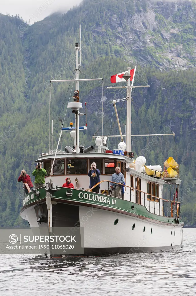 Photographers aboard Columbia III prepare to photograph a waterfall cascading into Kynoch Inlet. Fjordland, Great Bear Rainforest, Northern British Co...