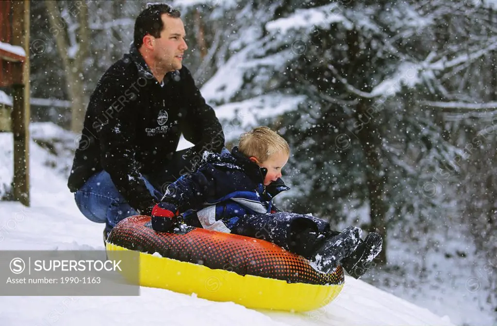 The anticipation of a big ride down the hill: father and son tubing in winter, British Columbia, Canada