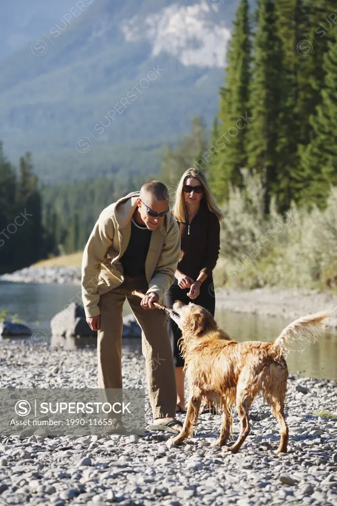 A young married couple playing with their dog, British Columbia, Canada.