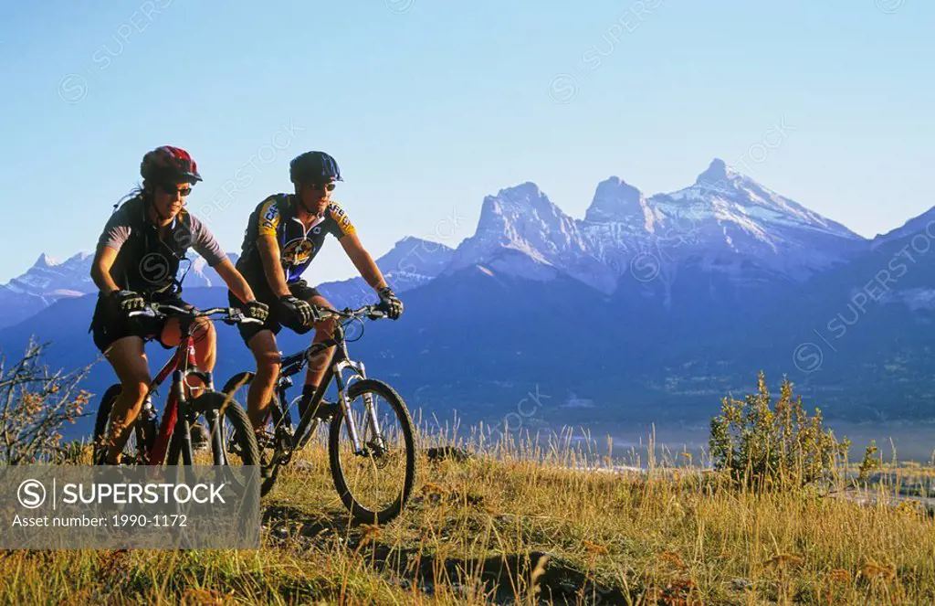 Mountain bikers and the Three Sisters mountains, Canmore, Alberta, Canada