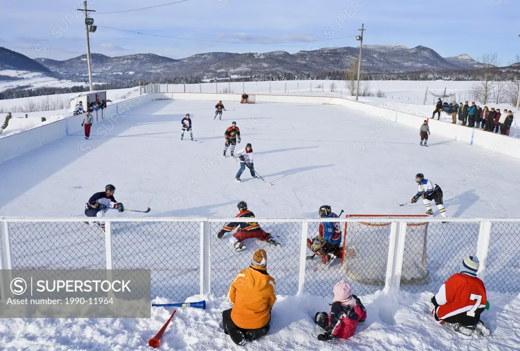 Hockey game played on a village outdoor rink on a pleasent saturday afternoon, Les Les Éboulements, Quebec, Canada