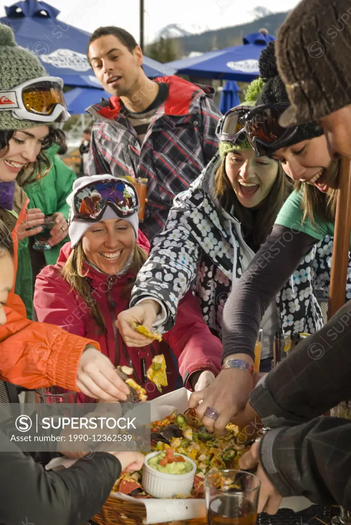 Group enjoys an apres-ski snack and drink on the outdoor deck of the Garibaldi Lift Company bar in Whistler, BC