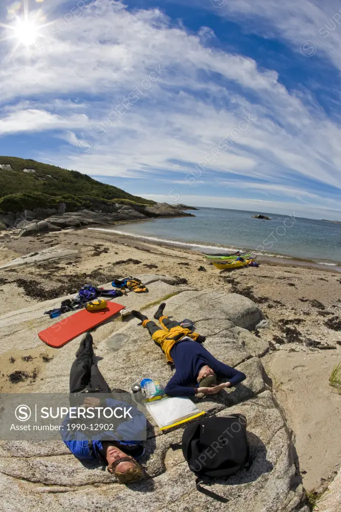 Two sea kayaker enjoying the movement of the cloulds in the Maritime sky ,Newfoundland, Canada.