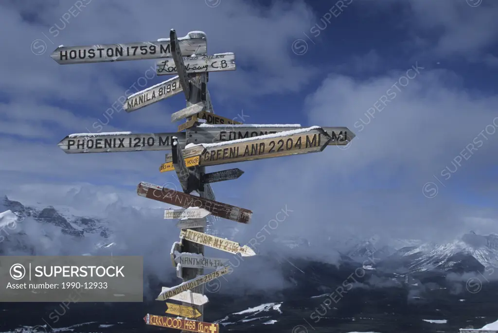 Signs pointing in all sort of directions and stating distances, with a magnificent backdrop of the rocky mountains, British Columbia, Canada.