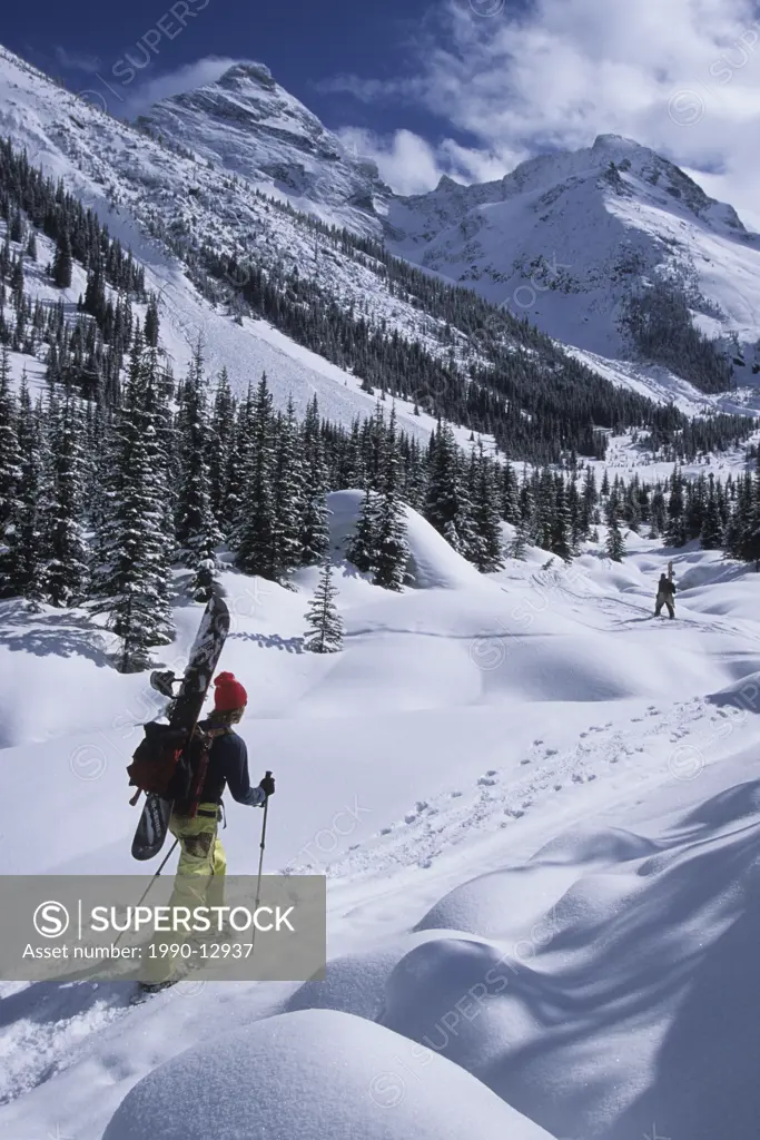 A snowboarder bootpacking up a valley in rogers pass, British Columbia, Canada.