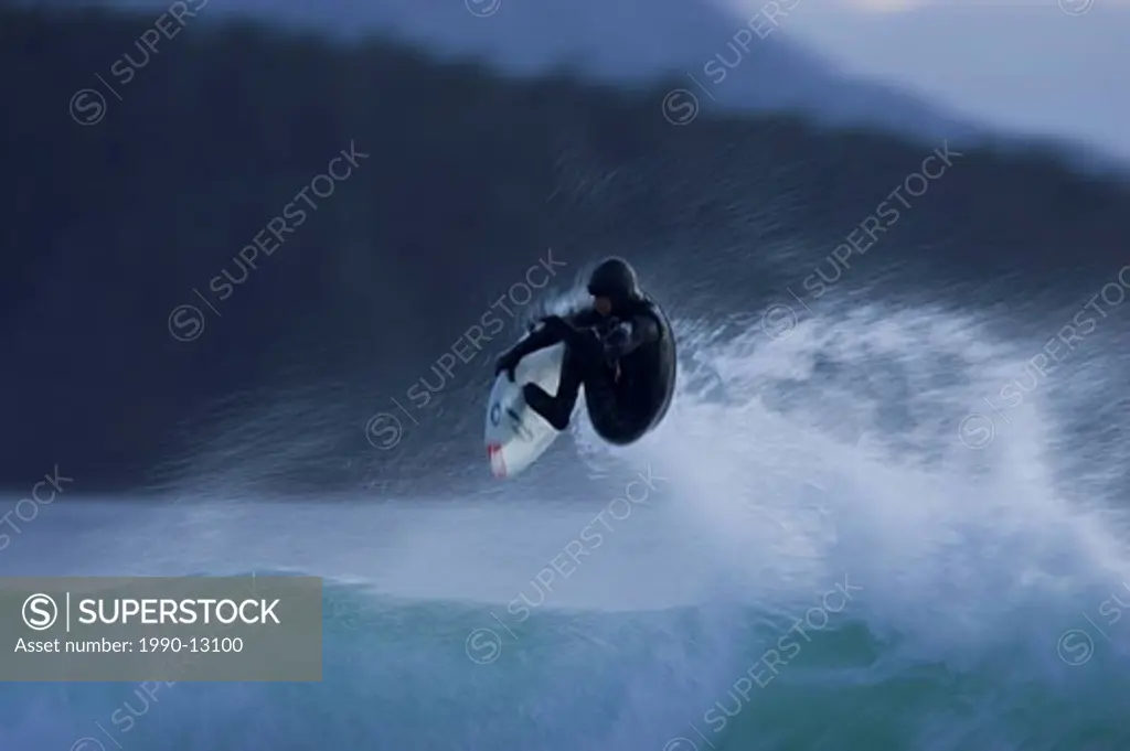 A surfer catching air in winter near Tofino, Vancouver Island, British Columbia, Canada