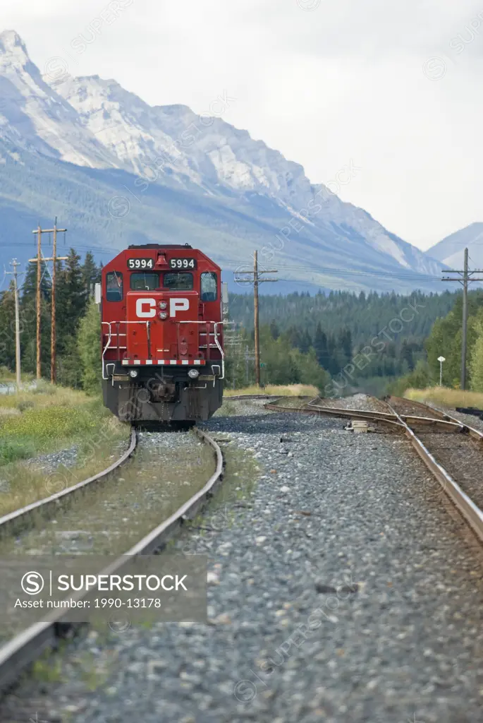 A CP Rail locomotive sits on the tracks with Mount Rundle in the background near Canmore Alberta, Canada.