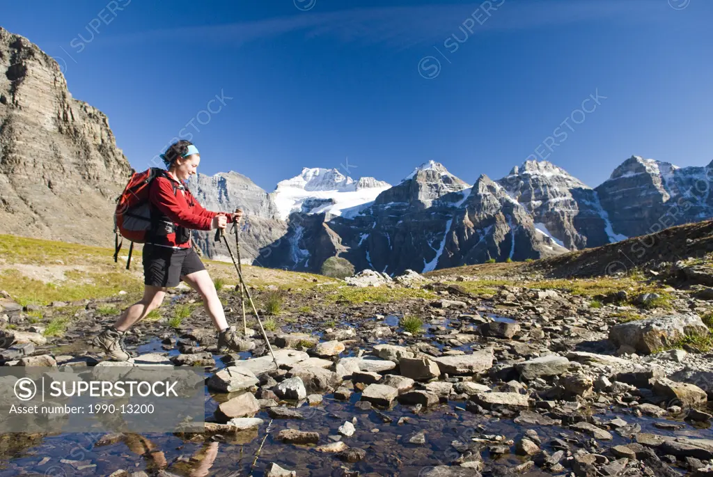 A female hiker crossing a creek in Larch Valley near Moraine Lake in Banff National Park, Alberta, Canada.