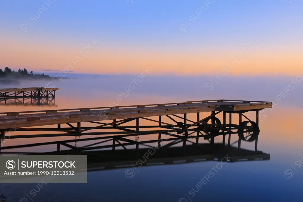 Dock in fog at sunrise on Sturgeon Lake Williamson Provincial Park Alberta Canada